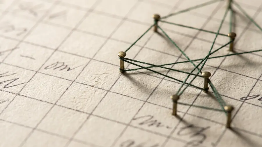 Brass pins and thread stretched across ruled grid paper