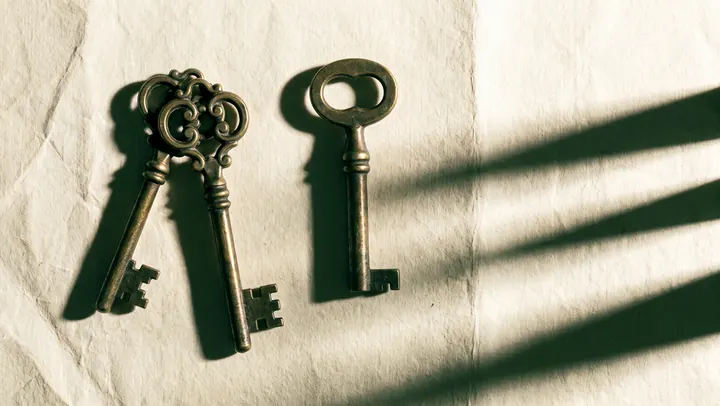 Three antique keys laid on paper in raking light