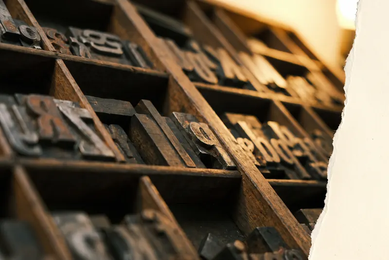 A wooden letterpress type case filled with sorts, seen in low warm light